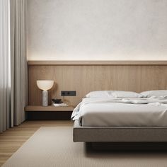 a bed with white sheets and pillows in a room next to a wall mounted lamp