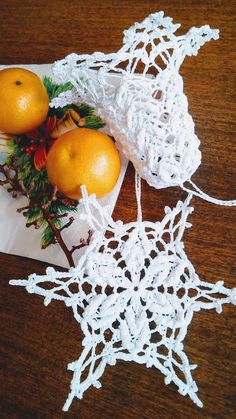 two oranges are sitting on top of some crocheted snowflakes