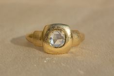 a gold ring with a faceted stone in the center on a plain surface,