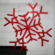 a red snowflake hanging from the side of a white brick wall next to a fireplace