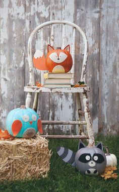 an old chair with two little raccoons sitting on top of it next to some hay