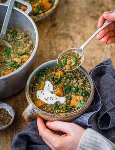 a person holding a spoon over a bowl of lentils