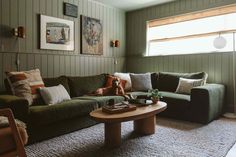 a living room with green couches and pictures on the wall above them, along with a coffee table