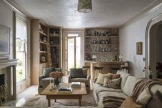 a living room filled with furniture and a fire place in front of a book shelf