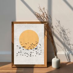 an art print with birds flying in front of a yellow sun on a white wall