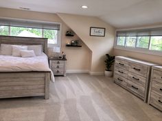 a bedroom with a bed, dressers and windows in the corner on top of it