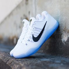 a pair of white and black nike shoes sitting on the side of a cement wall