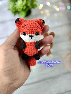 a hand holding a small crocheted red fox doll in it's right hand