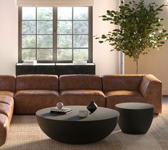 a living room with leather furniture and a large window in the corner, along with a coffee table