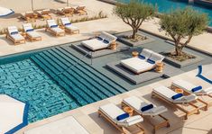 an outdoor pool with lounge chairs and umbrellas