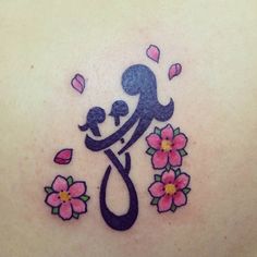 a woman with a tattoo on her back holding a baby in her arms and flowers around her neck