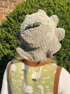 the back of a person wearing a sweater and vest with a stuffed animal on it