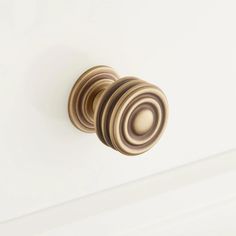 an image of a door knob on the side of a white cabinet with gold accents