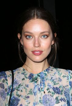 a close up of a person wearing a flowered shirt and holding a handbag