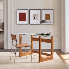 a glass table with two chairs next to it and pictures on the wall behind it