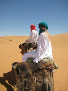 two people riding on the back of a camel