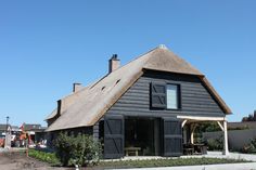 a house with a thatched roof and black shutters