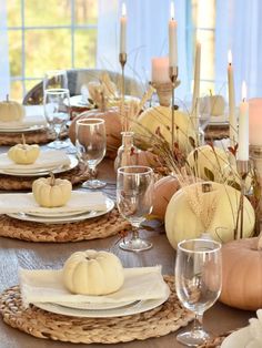 a table set for thanksgiving with white pumpkins and wheatstarts on the plates