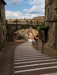 an alley way with stone buildings and cobblestone walkway leading up to the bridge