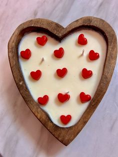 a heart shaped cake with red hearts on it's side in a wooden bowl