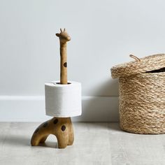 a giraffe shaped toilet paper holder next to a wicker basket with a wooden handle