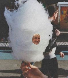 a person holding up a large cotton ball with a face on it's side