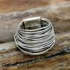 a stack of silver rings sitting on top of a wooden table next to a piece of metal