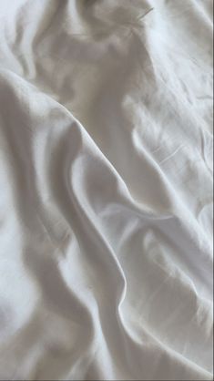 an unmade bed with white sheets and pillows