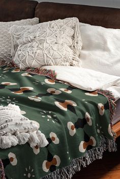 an unmade bed with pillows and blankets on top of it, next to a brown couch