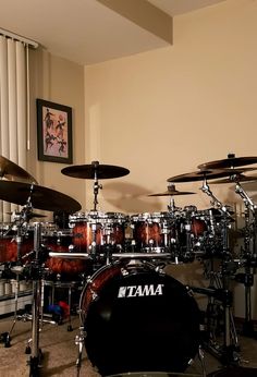 a set of drums sitting on top of a floor next to a window with curtains