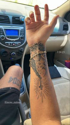 a person with a tattoo on their arm and wrist holding up his hand in the car