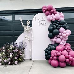 there is a skeleton standing next to a large balloon arch