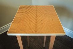 a wooden table sitting on top of a hard wood floor next to a white wall