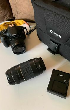 the camera is sitting next to two other cameras and a bag on top of a table