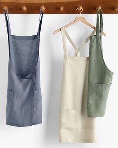 three aprons hanging on a wooden rail