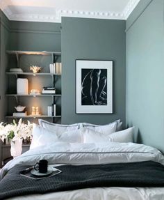 a bed with white sheets and pillows in a bedroom next to a book shelf filled with books