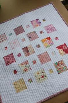 a quilted table topper with squares and flowers on it