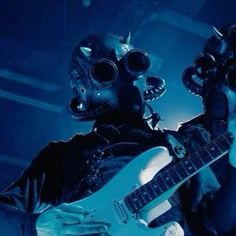 a man in a gas mask playing an electric guitar