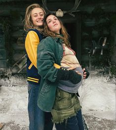 two women standing next to each other in front of a building with antlers on it