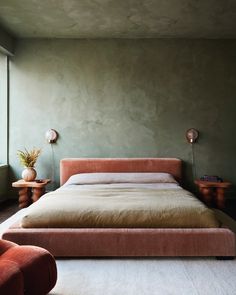 a bed sitting in the middle of a bedroom next to a red chair and table