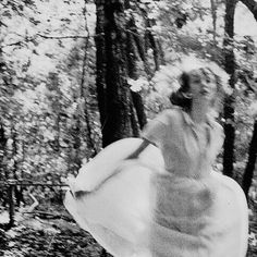 a woman in a dress is running through the woods