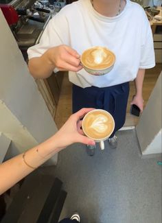 two people holding coffee cups in their hands