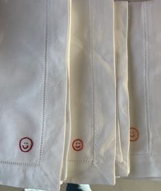 four white napkins with embroidered smiley faces on them are sitting next to each other