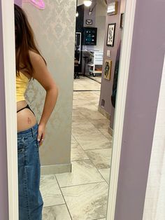 a woman standing in front of a mirror with her stomach exposed and looking at herself