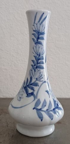 a blue and white vase sitting on top of a wooden table next to a wall