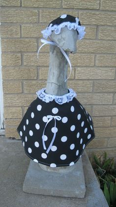 a mannequin wearing a polka dot dress and bonnet on top of a cement block