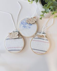 three embroidered ornament hanging on a table next to a vase filled with flowers