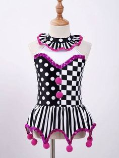 a black and white dress with pink pom poms on the bottom is sitting on a mannequin