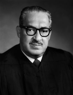 a black and white photo of a man in a judge's robe with glasses