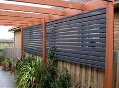 an outdoor area with wooden fence and plants on the side of the building, along with brick walkway